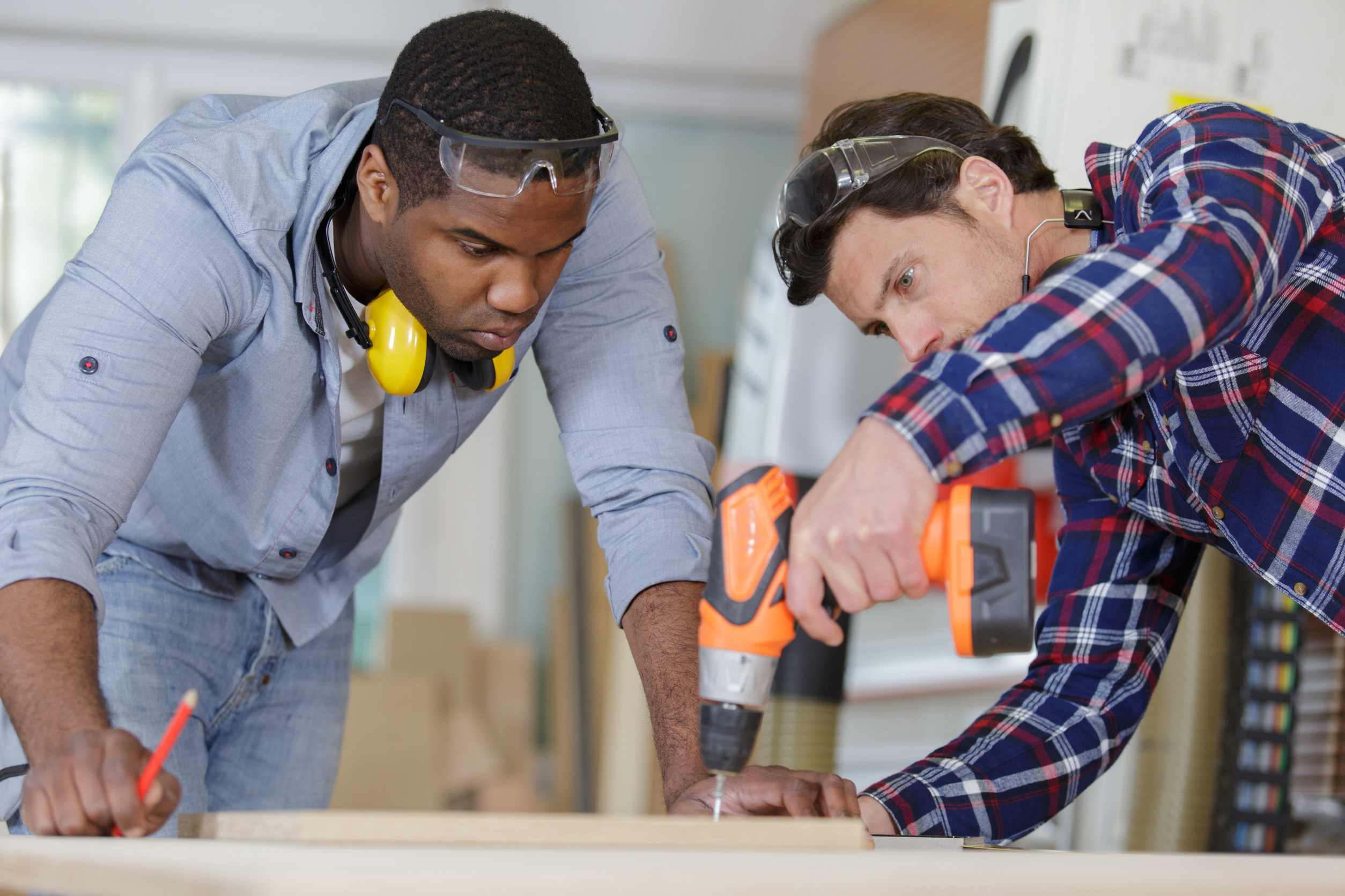 carpenter and carpenter’s assistant drilling wood